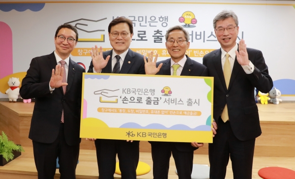 김학수 금융결제원장, 최종구 금융위원장, 윤종규 KB금융그룹 회장, 허인 KB국민은행장이 손으로 출금 서비스 출시 기념식에서 포즈를 취하고 있다